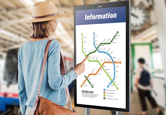 A woman is touching on the digital screen to view the metro informtation in train station.
